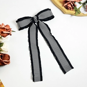 Detail of houndstooth bow hair clip with ruffled edges and long flowing ribbons