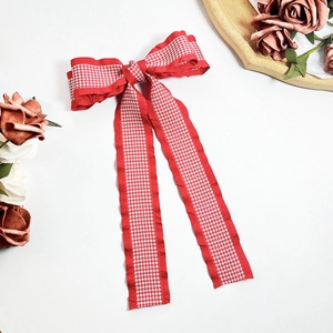 Detail of red houndstooth bow hair clip with long ribbons and soft woven texture