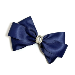 Detail van de marineblauwe satijnen strik haarclip met een sprankelende strasstenen kern