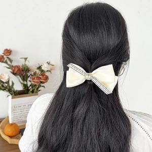 Elegant cream satin bow hair clip with crystal center and vintage script detail