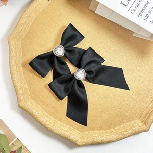 Elegant pair of black satin bow hair clips featuring heart-shaped crystal centerpieces