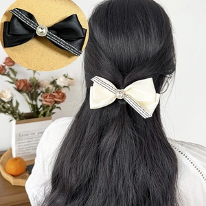 Detail of elegant satin bow hair clip with central rhinestones and cursive lettering print