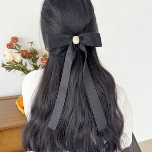 Rear view of a model wearing a black ribbon bow hairclip with sparkling rhinestone detail