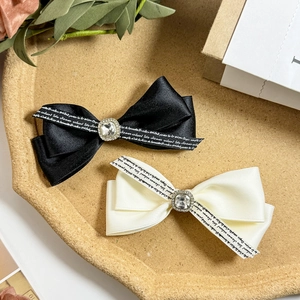 Elegant satin bow hair clips set in black and off-white with rhinestone and letter ribbon