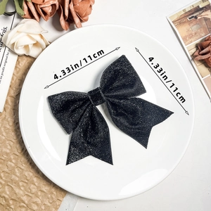 Detail of 4.33-inch sparkling black glitter bow hair clip on an elegant ceramic plate
