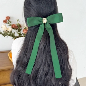 Dark green satin bow hair clip with crystal gem on elegant wavy hair back view