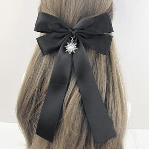 Elegant black satin bow hair clip with silver sun pendant on long brown hair