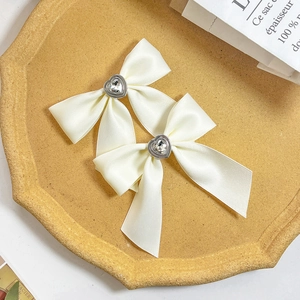 Elegant set of 2 cream satin bow hair clips featuring a heart-shaped crystal centerpiece