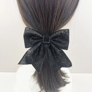 Sparkling black bow hair clip for women with glitter fabric shown on a ponytail