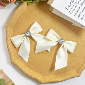 Detail of cream silk bow hair clips with heart rhinestones on a French style tray