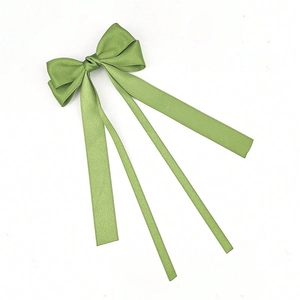 Detail view of sage green matte satin ballet-style hair clip with triple ribbon streamers