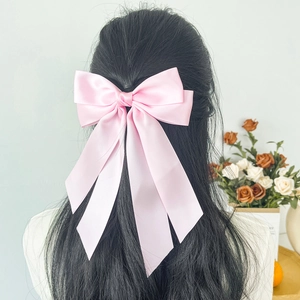 Elegant light pink satin ribbon bow hair clip for women styled on a ponytail hairstyle