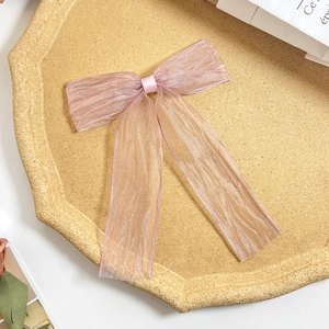 Detail einer rosa Organza-Haarspange mit transparenter Faltenstruktur auf Tablett