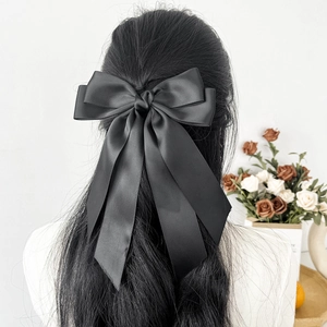 Close-up of a large black satin bow hair clip with long ribbons on the back of head