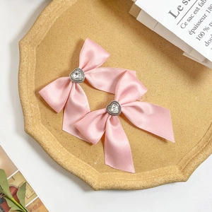 Detail view of pink satin bow hair clips with heart-shaped crystal embellishments