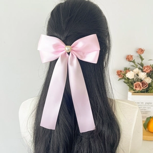 Nœud en satin rose avec perle en cœur porté à l'arrière de la tête pour femme