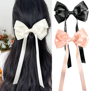 Detailaufnahme langer Satin-Haarschleifen-Clips in den Farben Creme, Schwarz und Rosa