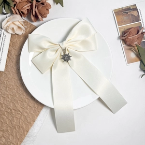 Close-up of cream satin bow hair clip with vintage sun pendant on a decorative tray