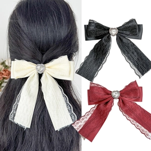 Detailed macro view of lace ribbon hair clips with crystal heart center in three colors