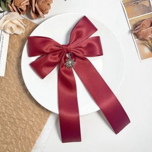 Macro shot of retro sun pendant on vintage wine red satin ribbon bow hair clip