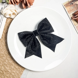 Close-up of elegant black glitter bow hair clip on a vintage decorative background