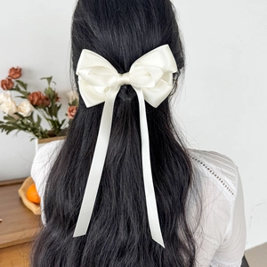 Eleganter weißer Satin-Schleifen-Haarclip mit langen Bändern auf Damenfrisur