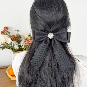 Elegant black lace bow hair clip featuring a heart-shaped crystal on dark hair