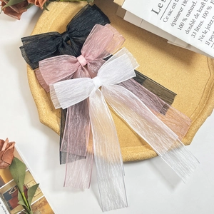 Drei übergroße Organza-Haarschleifen in Schwarz, Rosa und Weiß auf einem beigen Tablett