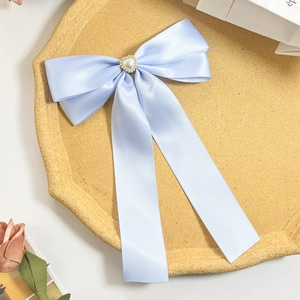 Détail de la pince à cheveux noeud en satin bleu clair avec perle en forme de coeur