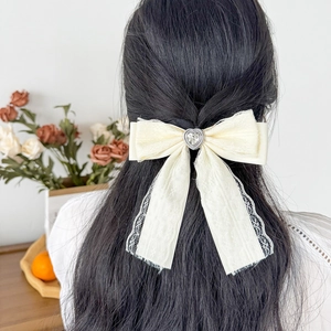 Detailed view of cream lace bow hair clip with heart crystal on model hairstyle