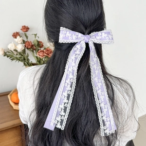 Detail einer eleganten lila Spitzen-Haarschleife mit langen Bändern am Modell