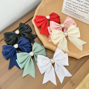 Detailed close-up of colorful satin bow hair clips with heart pearl and rhinestone centers