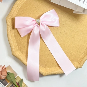 Vue détaillée du nœud en satin rose avec perle en cœur sur un plateau vintage
