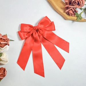Detail of red satin bow hair clip with long streamers and elegant glossy finish