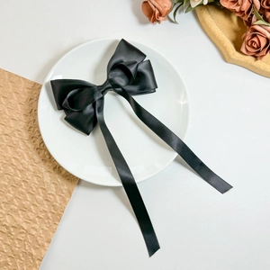 Detailaufnahme einer schwarzen Satin-Schleife Haarspange mit eleganten langen Bändern auf Teller