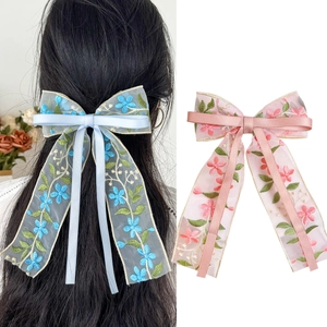 Detail of embroidered floral ribbon hair clips in light blue and pink mesh fabric