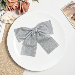 Silver sequined bow hair clip on white ceramic plate with elegant vintage floral background