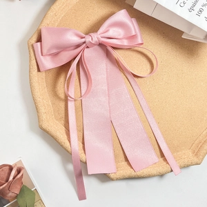 Dettaglio del fermaglio per capelli con fiocco in raso rosa chiaro e nastri multistrato eleganti