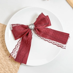 Detail of burgundy lace bow hair clip with heart rhinestone and long silk ribbons