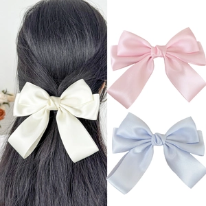Detail of silk satin bow hair clips with long ribbons in cream, pink, and blue colors