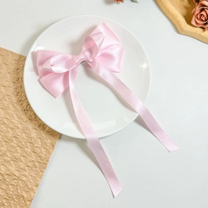 Nahaufnahme einer rosa Satinschleife Haarspange mit langen Bändern auf Dekoteller