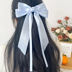 Light blue satin bow hair clip with long ribbons on wavy black hair from back view