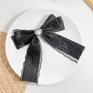 Detailed macro shot of a black lace bow hair clip with a centered heart crystal