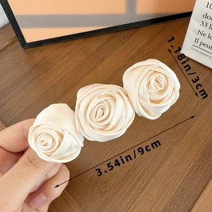 Close-up of three cream satin fabric roses with spring clip measuring 9cm in length
