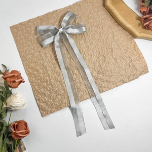 Detail der eleganten silbernen Seidenschleifen-Haarspange mit Bändern und Glitzerrändern