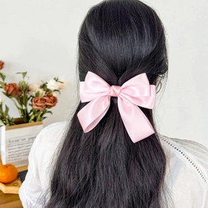 Rear view of a soft pink satin bow hair clip worn in hair for an elegant feminine style