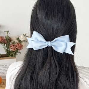 Elegant light blue double-layered satin bow hair clip worn on long black hair
