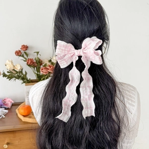 Fermaglio per capelli con fiocco a quadretti rosa e nastri lunghi su capelli neri