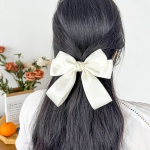Elegant white satin ribbon hair clip with double bow and long streamers on model