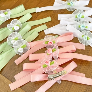 Fermagli per capelli a fiore in rosa bianco e verde su sfondo di legno rustico